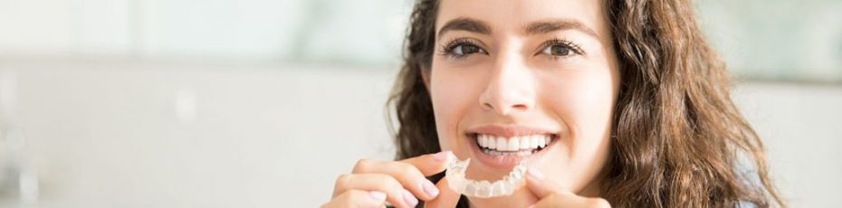 woman putting Invisalign braces on her mouth