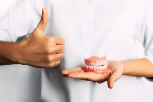 man holding dentures at Saby Dental